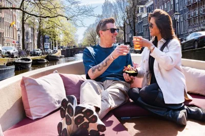 Scivola lungo i canali più antichi di amsterdam in una piccola barca con drink illimitati, formaggio gouda olandese e storie autentiche raccontate da una guida locale.