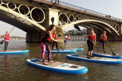 Feel the pulse of seville paddle surfing the guadalquivir, gliding under triana bridge, with a local guide, drinks in triana, and souvenir video included.
