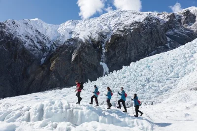 Fly by helicopter to franz josef glacier, hike with expert guides among blue ice, and hear local stories. includes gear, commentary, and round-trip flights.