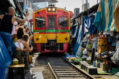 Feel the rush as a train passes through maeklong market, then drift by boat at damnoen saduak floating market. includes hotel pickup, guide, and thai treats.