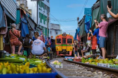 Feel the rush as the train passes inches from you at maeklong railway market, then ride a long-tail boat through damnoen saduak floating market. includes pickup and guide.