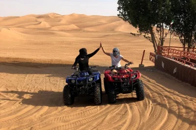 Vive la emoción de las dunas rojas de dubai al atardecer, monta en quad, prueba sandboarding y relájate con una cena bbq y show en un campamento en el desierto. incluye recogida.