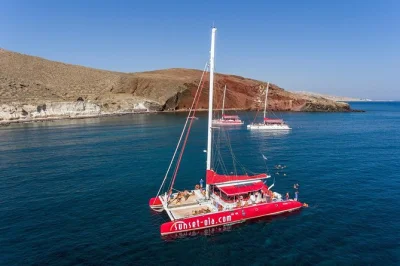 Découvrez santorin en catamaran avec baignades aux plages rouge et blanche, arrêt aux sources chaudes volcaniques, déjeuner bbq, boissons et transfert hôtel inclus.