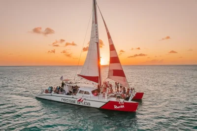 Navega la costa de aruba al atardecer en catamarán con cena tipo buffet, barra libre y sabores locales. incluye traslado y guía para una velada relajada.