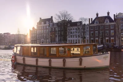 Scopri amsterdam sorseggiando drink locali e assaggiando snack olandesi mentre navighi tra i canali, la casa di anna frank e il magro ponte in un tour di 2 ore con guida dal vivo—coperte incluse.