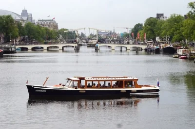 Float through amsterdam’s quiet canals at sunrise in a historic 1928 royal boat, with coffee, dutch treats, and a small group. includes heated cabin & restroom.