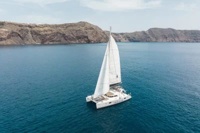Vivi la brezza marina con una crociera in catamarano a santorini, nuotando nelle sorgenti termali, gustando un pranzo bbq, bevande incluse e transfer andata e ritorno dall’hotel. naviga tra le spiag