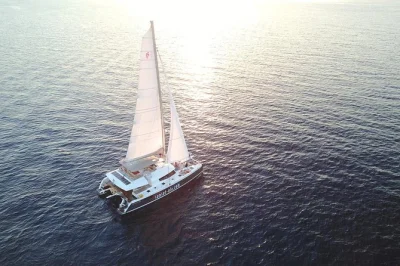 Feel the aegean breeze on a santorini sunset catamaran cruise, swim near volcanic beaches, enjoy greek bbq & drinks on board, with hotel pickup included.